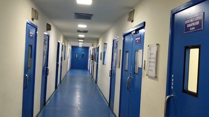 Coated tablet and capsule quarantine room at the Roorkee pharma plant, with differential pressure gauges above the doors